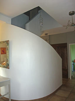 Un escalier en béton, plâtré, carrelé et placé au centre d'une pièce constitue un élément décoratif de la maison