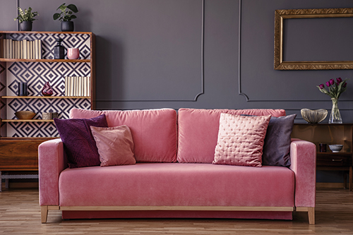 Dans un salon au gris profond tendance, ce canapé en velours rose réchauffe l’atmosphère et permet d’introduire une étagère de style scandinave.
