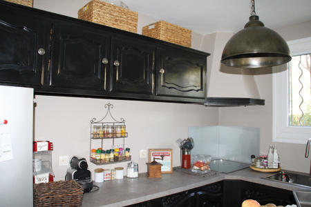   Une cuisine rustique à l’allure désormais contemporaine grâce à au relooking des placards en noir et au rajout d’un plan de travail stratifié gris